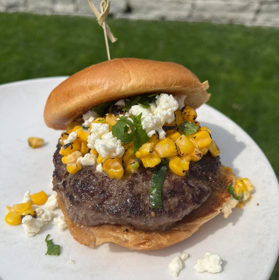 Summer burger topped with charred corn and feta